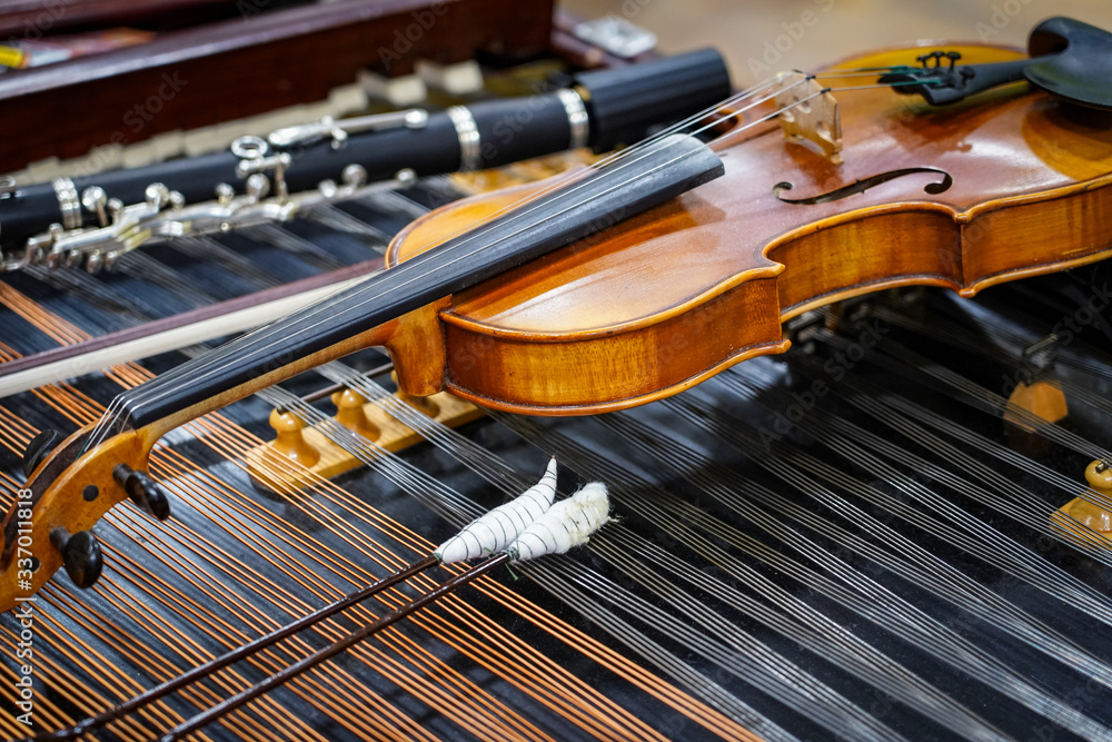 Fototapeta premium Antique violin and violin bow lying on dulcimer. Close up a violin instrument and cymbal before a concert. Music concept background