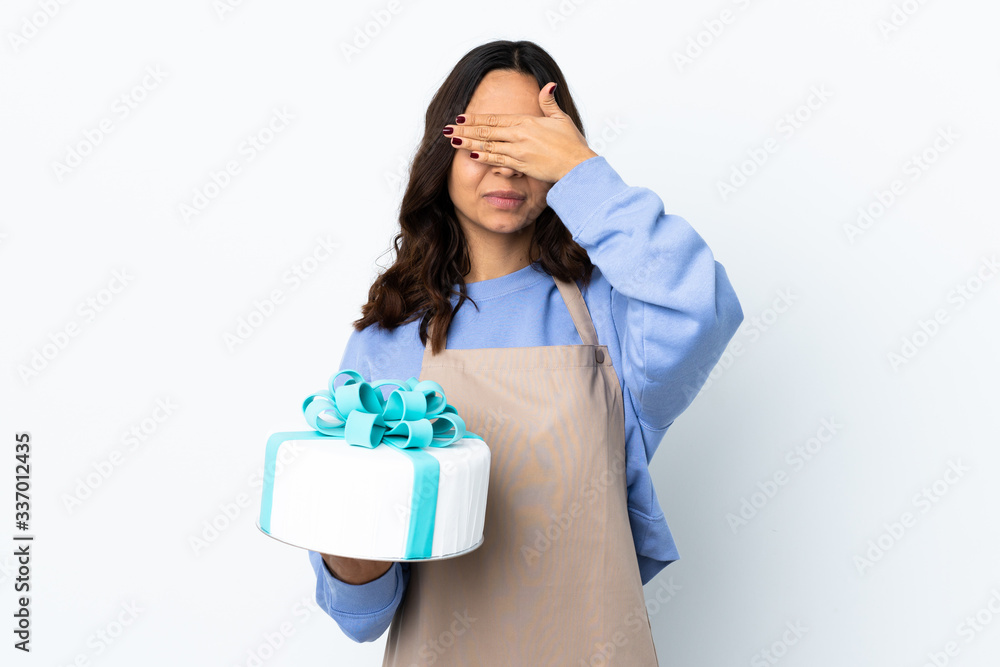 Pastry chef holding a big cake over isolated white background covering eyes by hands. Do not want to see something Pastry chef holding a big cake over isolated white background covering eyes by hands. Do not want to see something