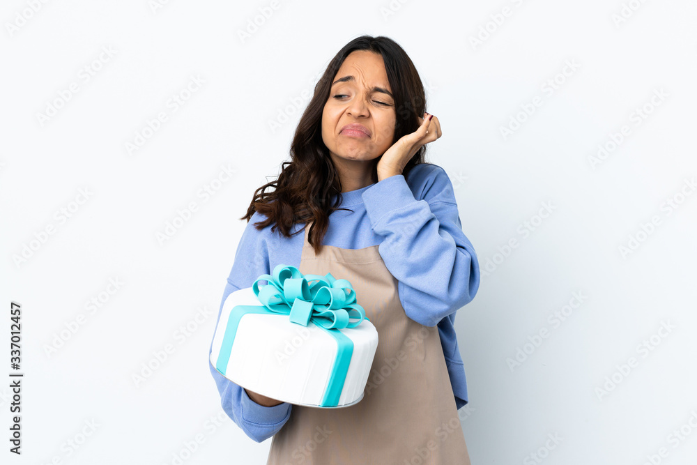 Pastry chef holding a big cake over isolated white background frustrated and covering ears Pastry chef holding a big cake over isolated white background frustrated and covering ears