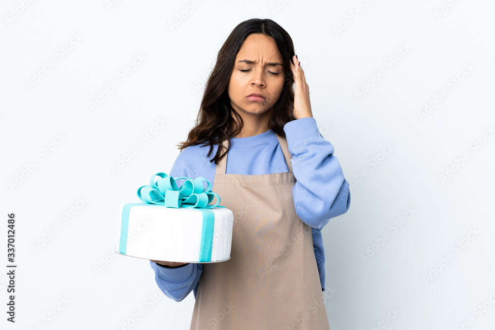 Pastry chef holding a big cake over isolated white background with headache Pastry chef holding a big cake over isolated white background with headache