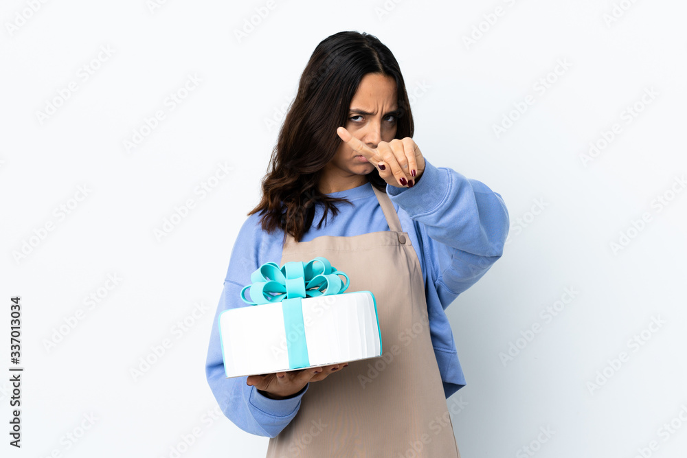 Pastry chef holding a big cake over isolated white background making stop gesture with her hand to stop an act Pastry chef holding a big cake over isolated white background making stop gesture with her hand to stop an act