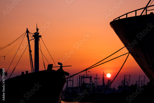 Fototapeta Naklejka Na Ścianę i Meble -  Silhouette many ships moored along the coast against colorful sunset sky background in evening time