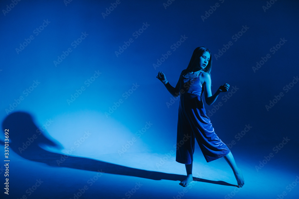 Naklejka premium Young stylish girl dancing in the Studio on a colored neon background. Classic dancer.
