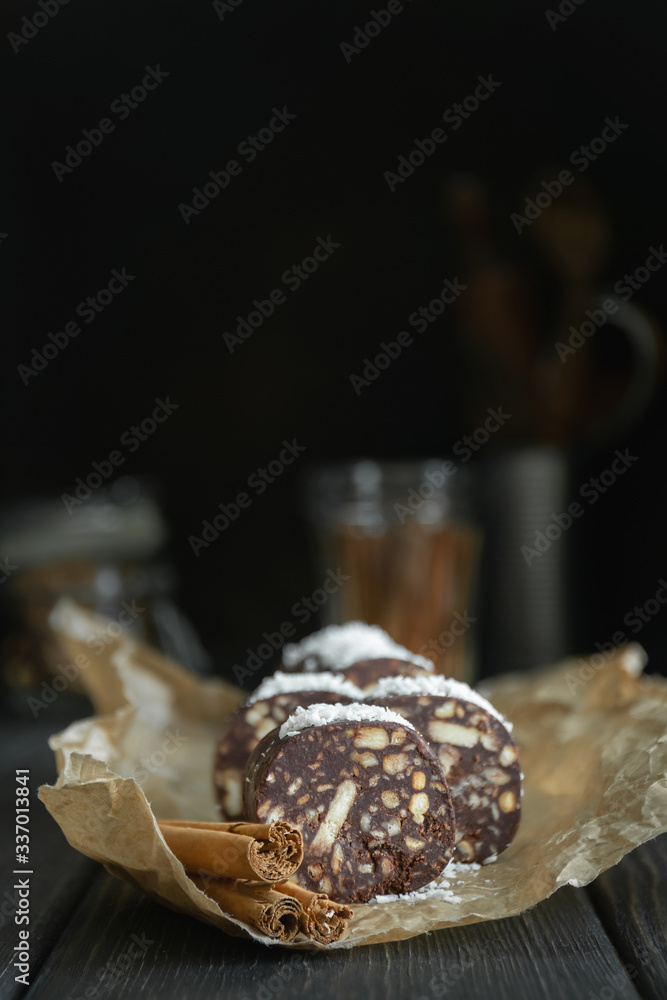 Vegetarian chocolate salami sprinkled with coconut and cut into slices on parchment.