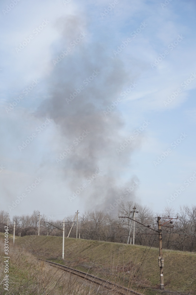 Obraz premium Black smoke in the sky above the railway.