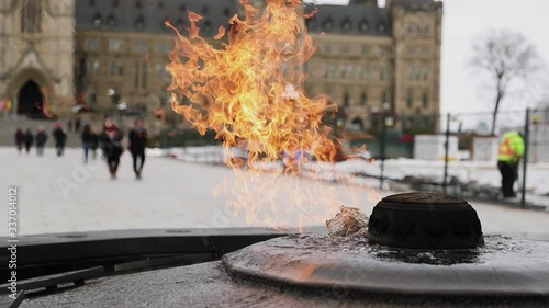 The beautiful gas fed flame of the Centennial Flame monument with center block in the background on Parliament Hill in Ottawa, Ontario, Canada. photo