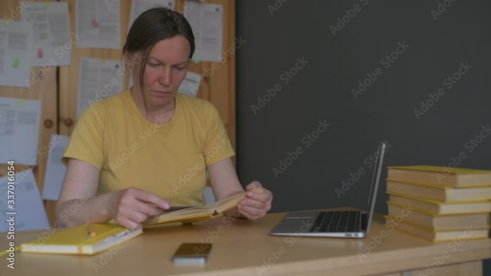 Female freelancer reading book in home office Female freelancer reading book in home office