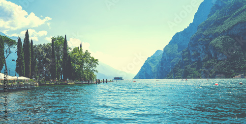 High mountains and shore, Lake Garda, Italy, Europe. Beautiful lakes of Italy - scenic Lago di Garda. Vintage tone filter effect with noise and grain.