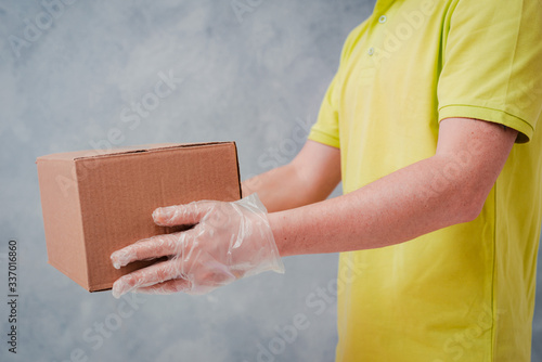 The courier holds cardboard boxes in disposable gloves. Contactless delivery during the quarantine period for coronavirus © shangarey
