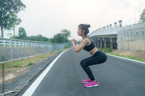 Asian women who exercise before exercising on public roads. Warm and warm women outside the house She is warming up, stretching the muscles. © Jukrachai