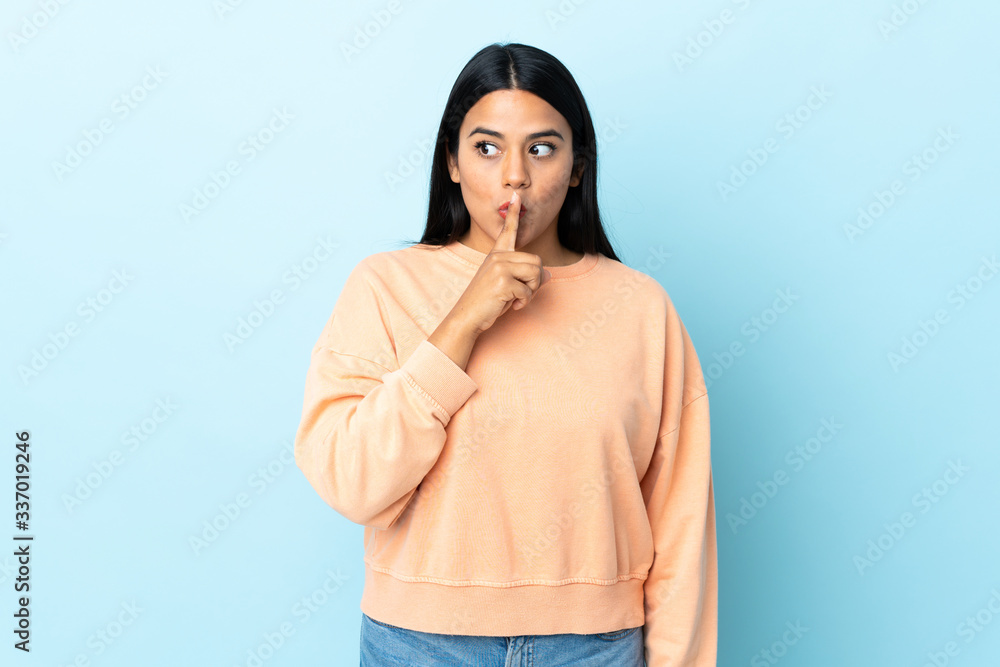 Young latin woman woman isolated on blue background showing a sign of silence gesture putting finger in mouth Young latin woman woman isolated on blue background showing a sign of silence gesture putting finger in mouth