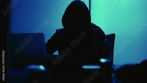 A computer programmer or hacker prints a code on a laptop keyboard to break into a secret organization system.