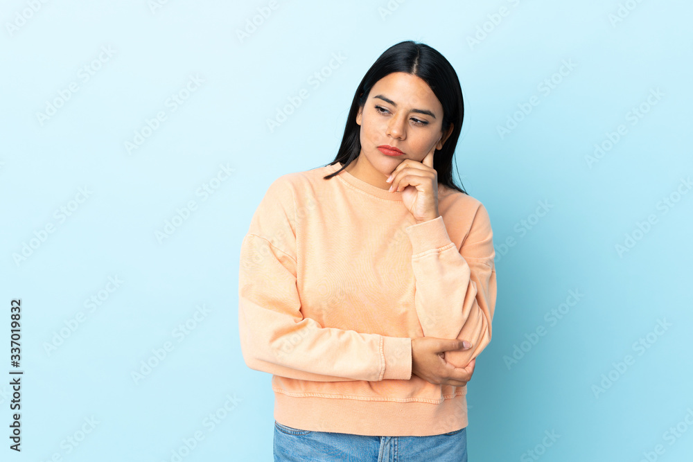 Young latin woman woman isolated on blue background with tired and bored expression Young latin woman woman isolated on blue background with tired and bored expression