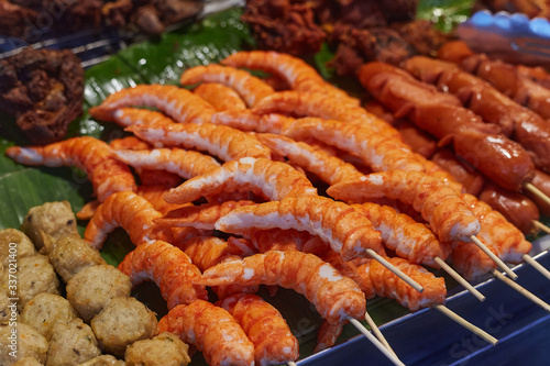 Prawn, meat balls and sausages on sticks in a sheet pan on street food market in Phuket island, Thailand, close up. 