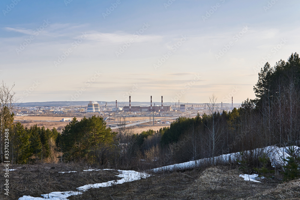 industrial landscape in early spring with a power station in the valley and the heating main leading from it