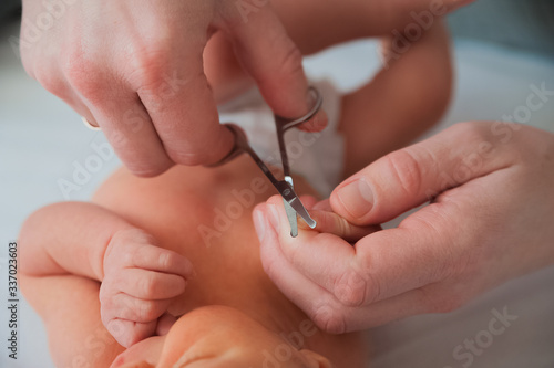 Father cuts the newborn   s nails. Manicure a child close-up. Newborn baby care concept.