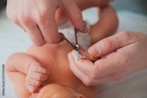 Father cuts the newborn   s nails. Manicure a child close-up. Newborn baby care concept.