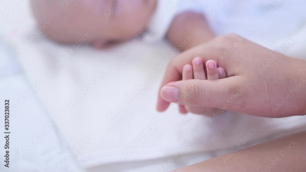 Hand of sleeping baby in the hand of mother on the bed, baby and mom concept. Hand of sleeping baby in the hand of mother on the bed, baby and mom concept.