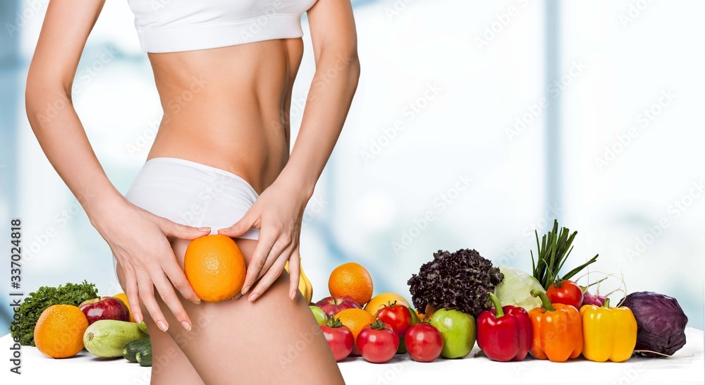 Female slender body in sport underwear holding orange Female slender body in sport underwear holding orange