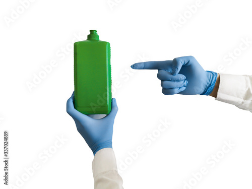 Hands in blue medical gloves are holding an antiseptic in a green bottle. Cleaning gloves with an antiseptic. Protecting hands with gloves in a pandemic.