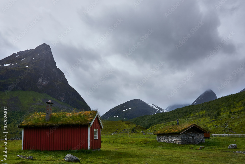 Traditionelle norwegische rote Holzhütte inmitten der beeindruckenden Landschaft des Geiranger Fjords.