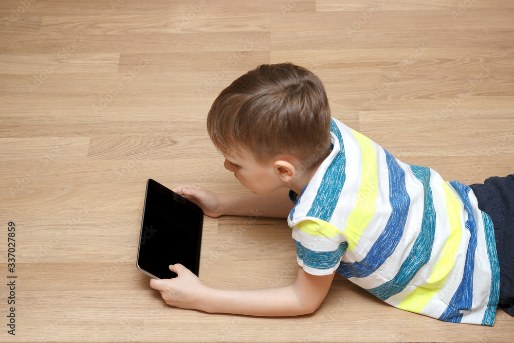Modern generation. The child plays games or watches cartoons. A boy is playing with his tablet. Modern generation. The child plays games or watches cartoons. A boy is playing with his tablet.