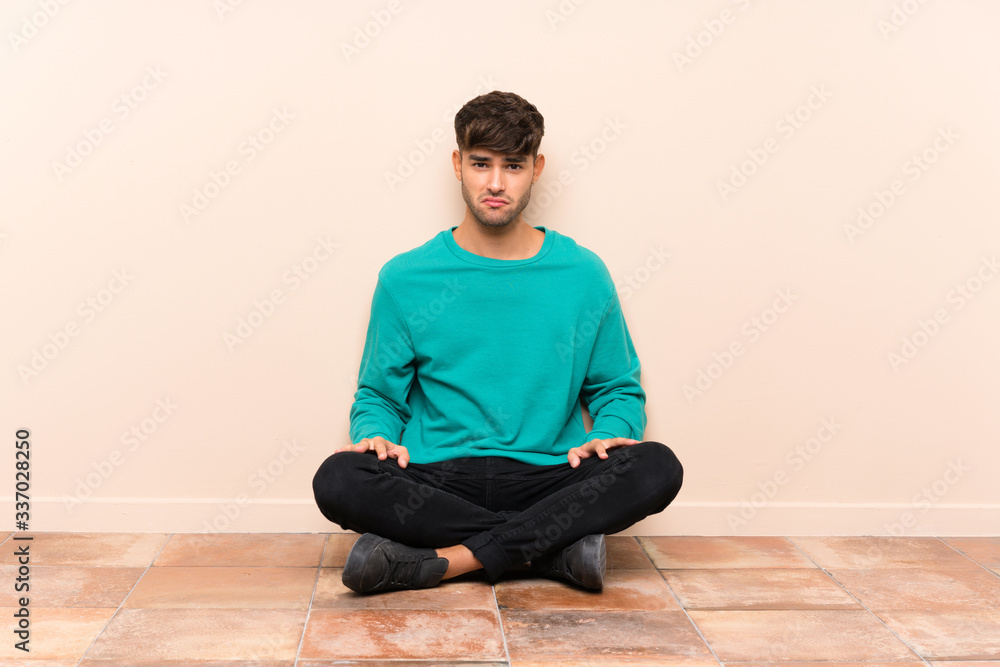 Young handsome man sitting on the floor sad Young handsome man sitting on the floor sad