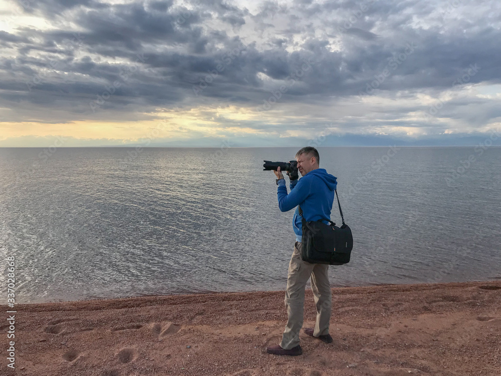 Obraz premium Рhotographer pointing camera at landscape on lake background.