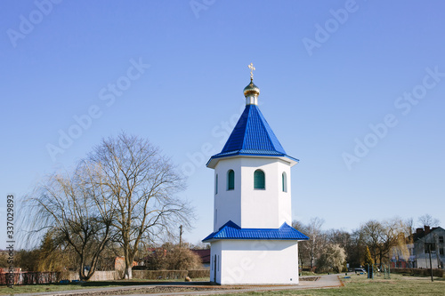 A small white Christian chapel with a blue roof. The building of the Russian Orthodox Church. photo