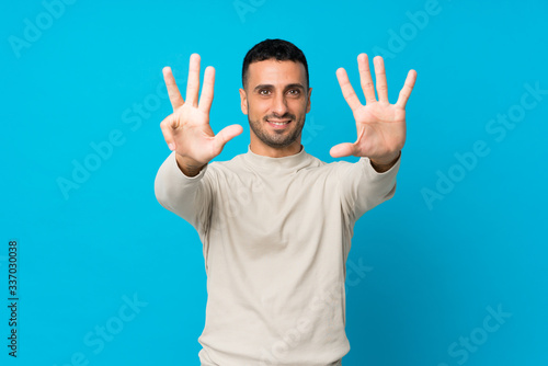 Young man over isolated blue background counting nine with fingers © luismolinero