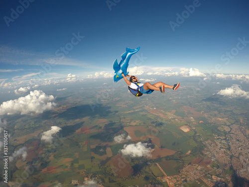 Parachutist holding an inflatable shark in free fall.