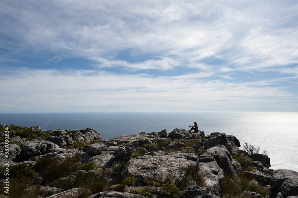 JUdas peak, cape town, south africa gril sitting by edge looking out over water JUdas peak, cape town, south africa gril sitting by edge looking out over water