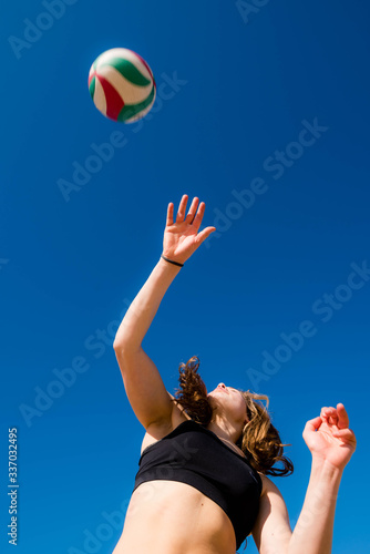 pretty young athletic woman playing volleyball on sunny beach © Image'in