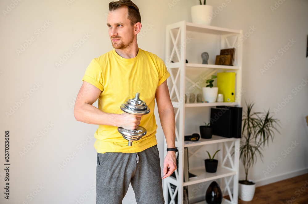 Athletic guy shakes biceps using iron dumbbells Athletic guy shakes biceps using iron dumbbells
