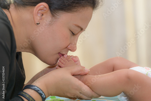 Happy Mother kissing Baby's feet