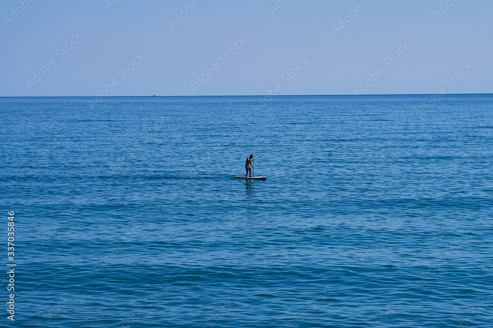 Man on sup surfing board at sea