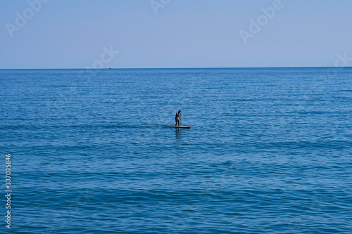 Man on sup surfing board at sea © Nicolaos