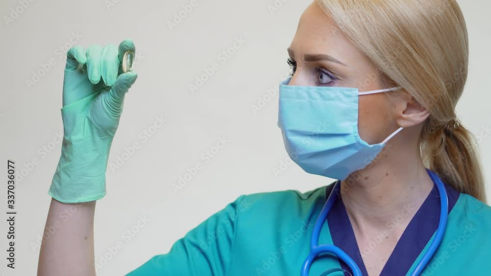 medical doctor nurse woman wearing protective mask and rubber or latex gloves - holding pills medical doctor nurse woman wearing protective mask and rubber or latex gloves - holding pills