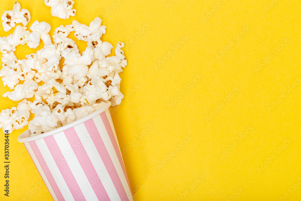 Popcorn bucket on yellow background. Movie or TV background. Top view Copy space