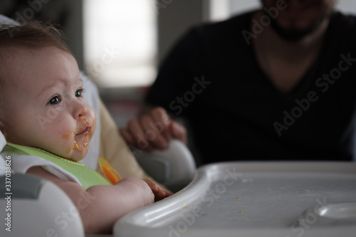 Baby girl eating lunch with help of her father. photo