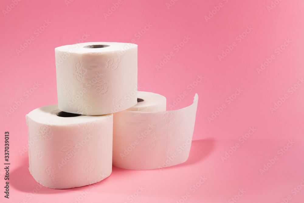 Three rolls of white toilet paper, isolated against pink background, with copy space available next to them. Three rolls of white toilet paper, isolated against pink background, with copy space available next to them.