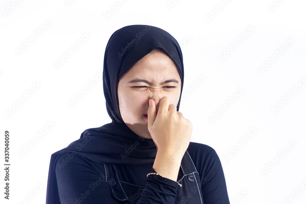 Portrait of frustrated moslem woman 20s pinching nose with disgust on his face due to bad smell isolated over white background Portrait of frustrated moslem woman 20s pinching nose with disgust on his face due to bad smell isolated over white background