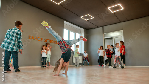 Fototapeta Naklejka Na Ścianę i Meble -  Breakdance. Full length portrait of a little girl standing on her hands while having a choreography class in the dance studio