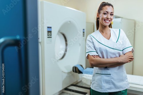 Happy female radiologist with arms crossed at medical examination room. photo