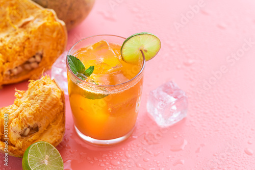 exotic fruit juice from Bel fruit or wooden Apple called in India Bel Ka Sharbat. cold fruit drink with ice on pink background. natural detox. vitamins for immunity photo