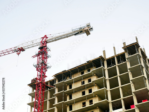 Construction crane near the building under construction. Tower crane on the background of construction. Construction site background.
