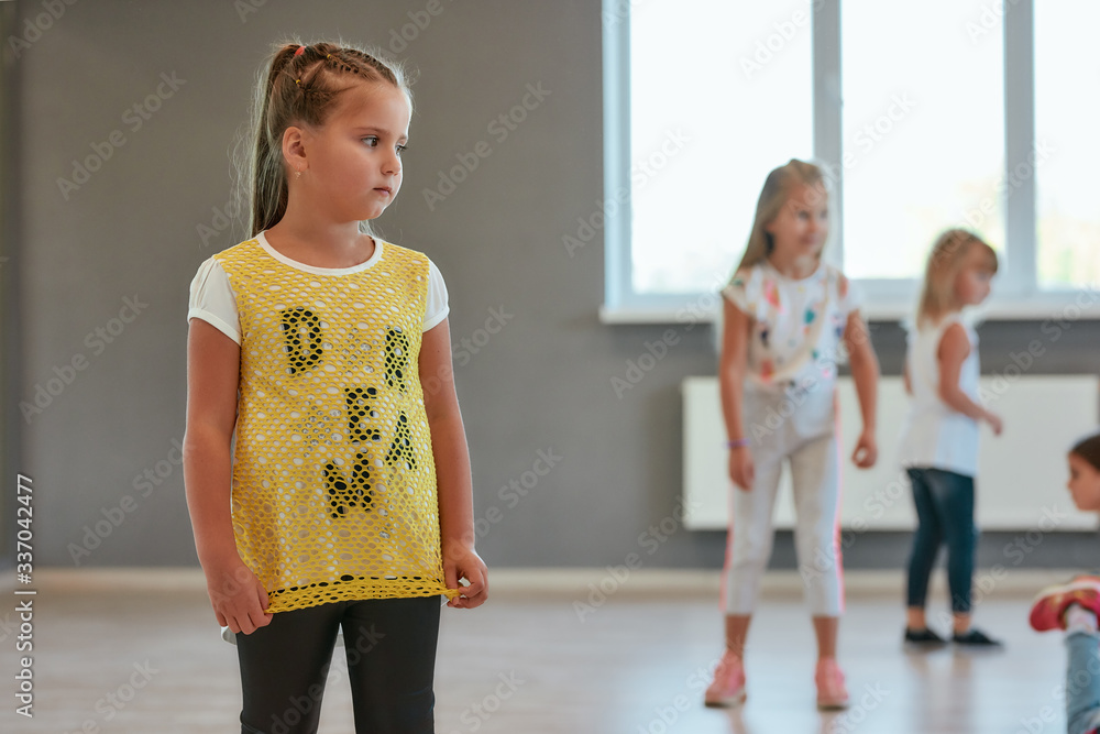 Portrait of a little cute girl looking away while having a choreography class. Group of children standing in the dance school Portrait of a little cute girl looking away while having a choreography class. Group of children standing in the dance school