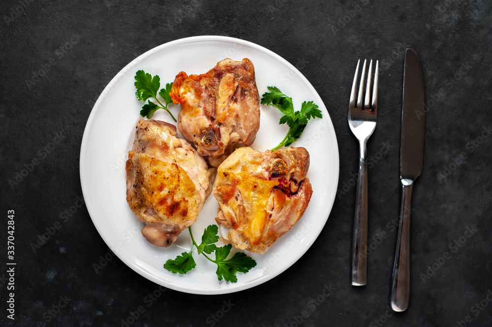 grilled chicken thighs on a white plate with spices on a stone background grilled chicken thighs on a white plate with spices on a stone background