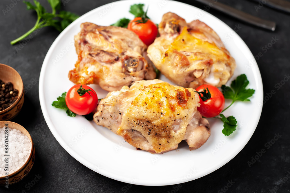 grilled chicken thighs on a white plate with spices on a stone background grilled chicken thighs on a white plate with spices on a stone background