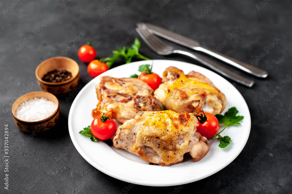 grilled chicken thighs on a white plate with spices on a stone background